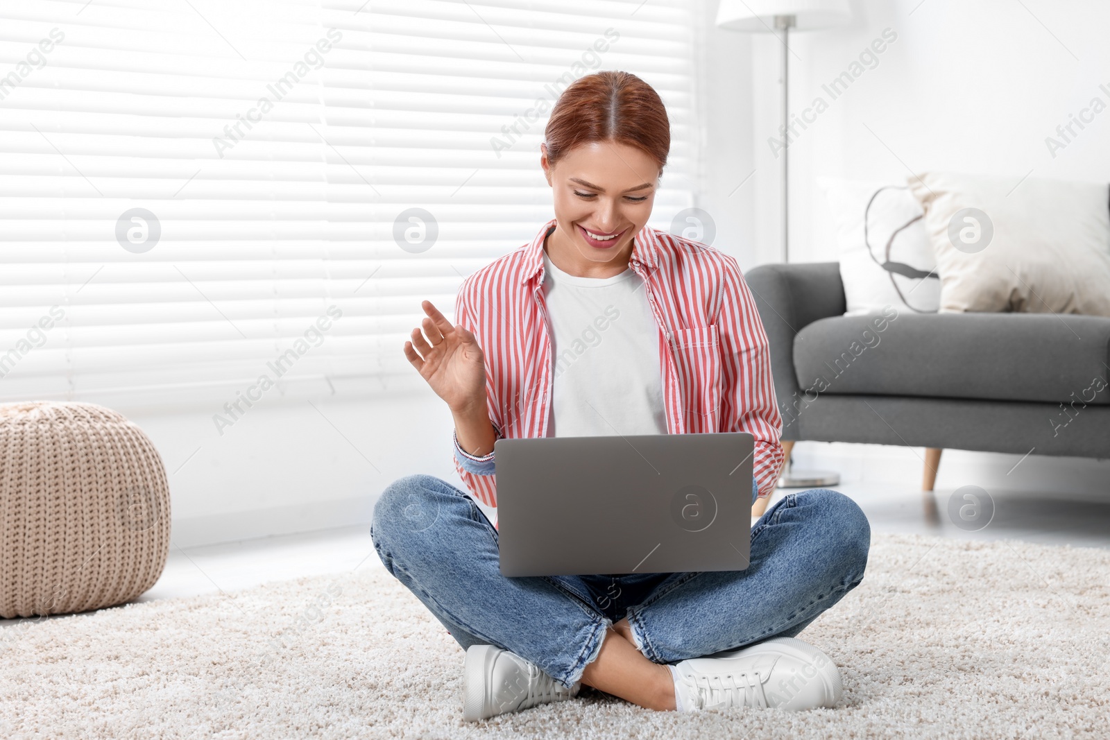 Photo of Woman waving hello during video chat via laptop at home