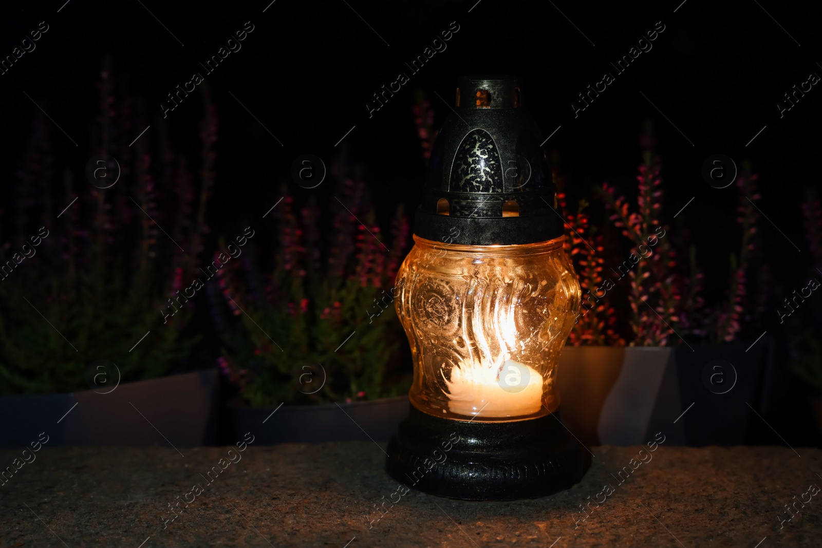 Photo of Grave lantern with burning candle on stone surface at night, space for text