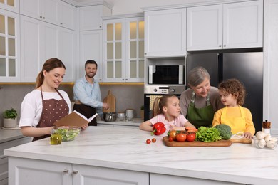 Photo of Family cooking by recipe book in kitchen