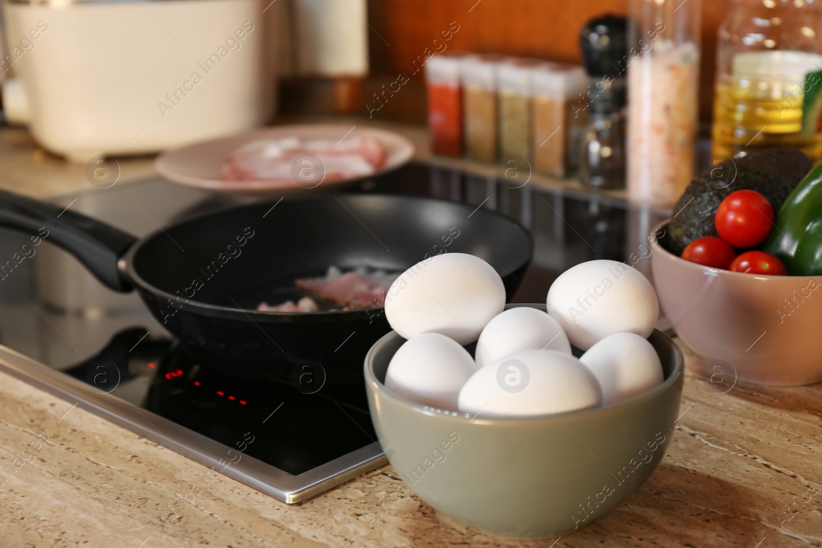 Photo of Many fresh eggs on wooden countertop in kitchen. Frying bacon for breakfast
