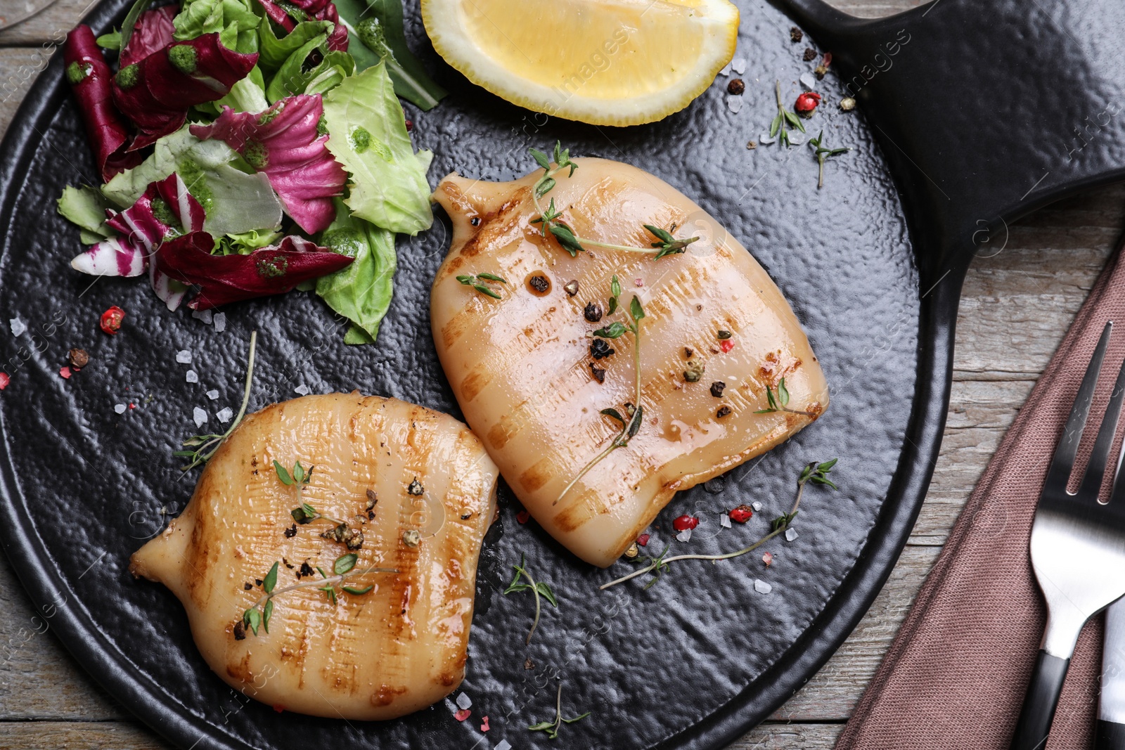 Photo of Grilled squid tubes served on wooden table, flat lay