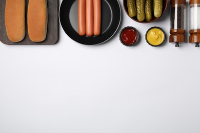 Different tasty ingredients for hot dog on white table, flat lay. Space for text