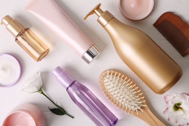 Flat lay composition with different hair products and accessories on white wooden table