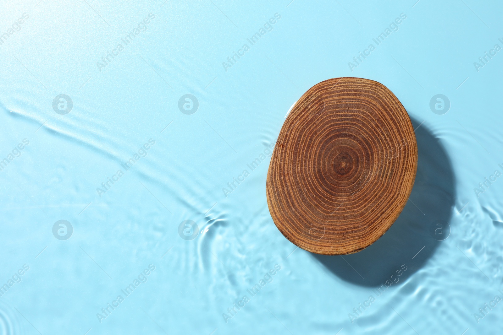 Photo of Presentation of product. Wooden podium in water on light blue background, top view. Space for text