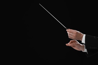 Photo of Professional conductor with baton on black background, closeup. Space for text