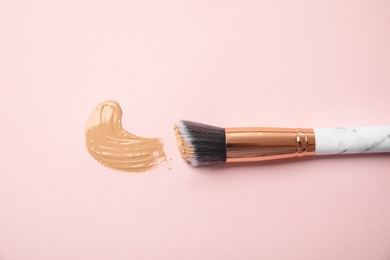 Photo of Sample of liquid foundation and makeup brush on pink background