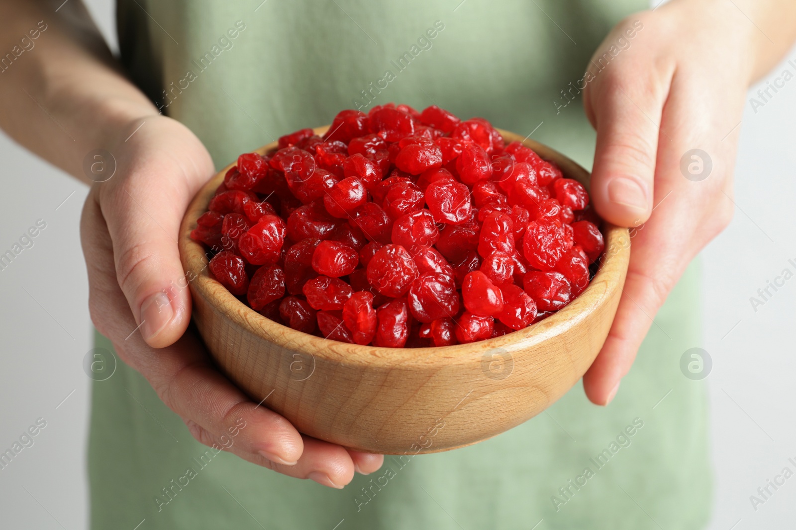 Photo of Woman holding bowl with tasty cherries on light background, closeup. Dried fruits as healthy food