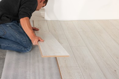 Photo of Professional worker installing new laminate flooring, closeup. Space for text