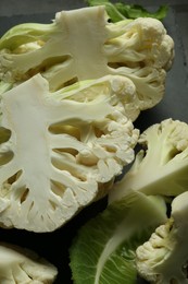 Photo of Cut fresh raw cauliflowers on black table, closeup