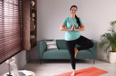 Photo of Overweight woman practicing yoga at home, space for text
