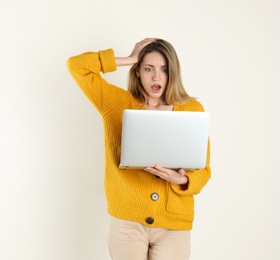 Photo of Portrait of shocked young woman in casual outfit with laptop on light background. Space for text