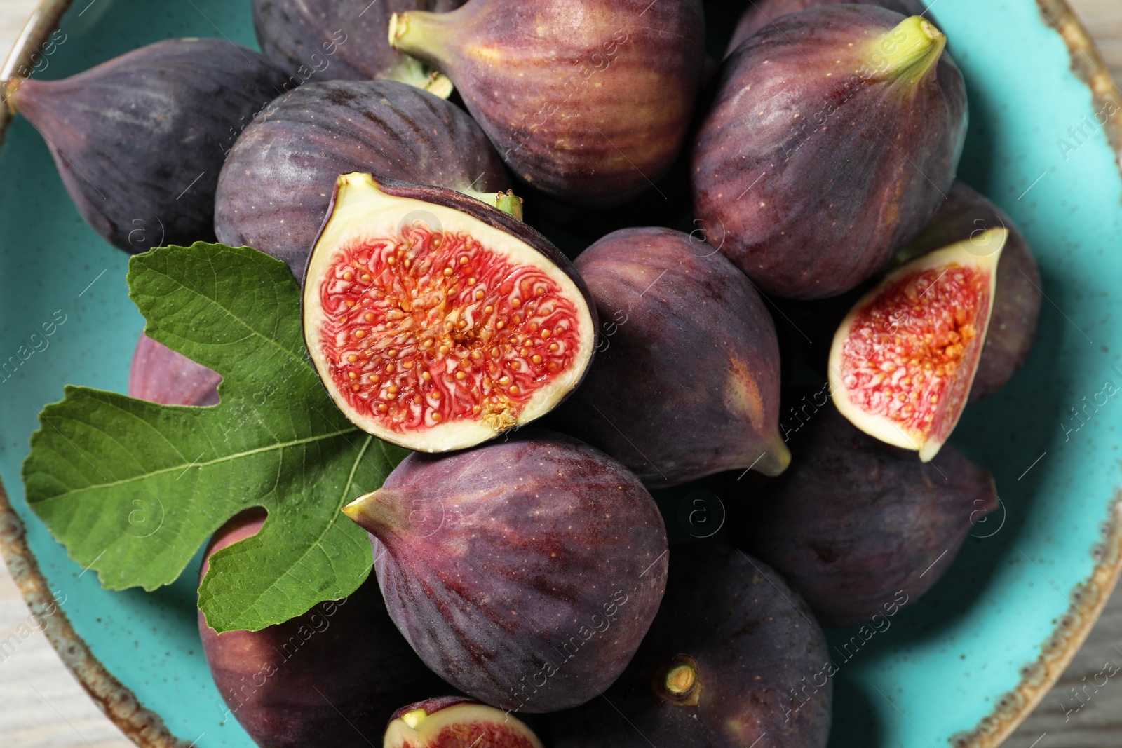 Photo of Plate with fresh ripe figs and green leaf on table, top view