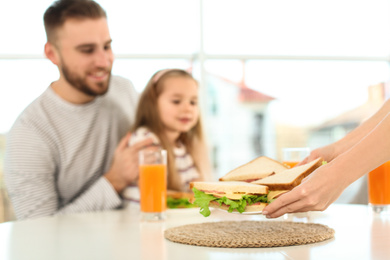 Happy family having breakfast with sandwiches in kitchen, closeup