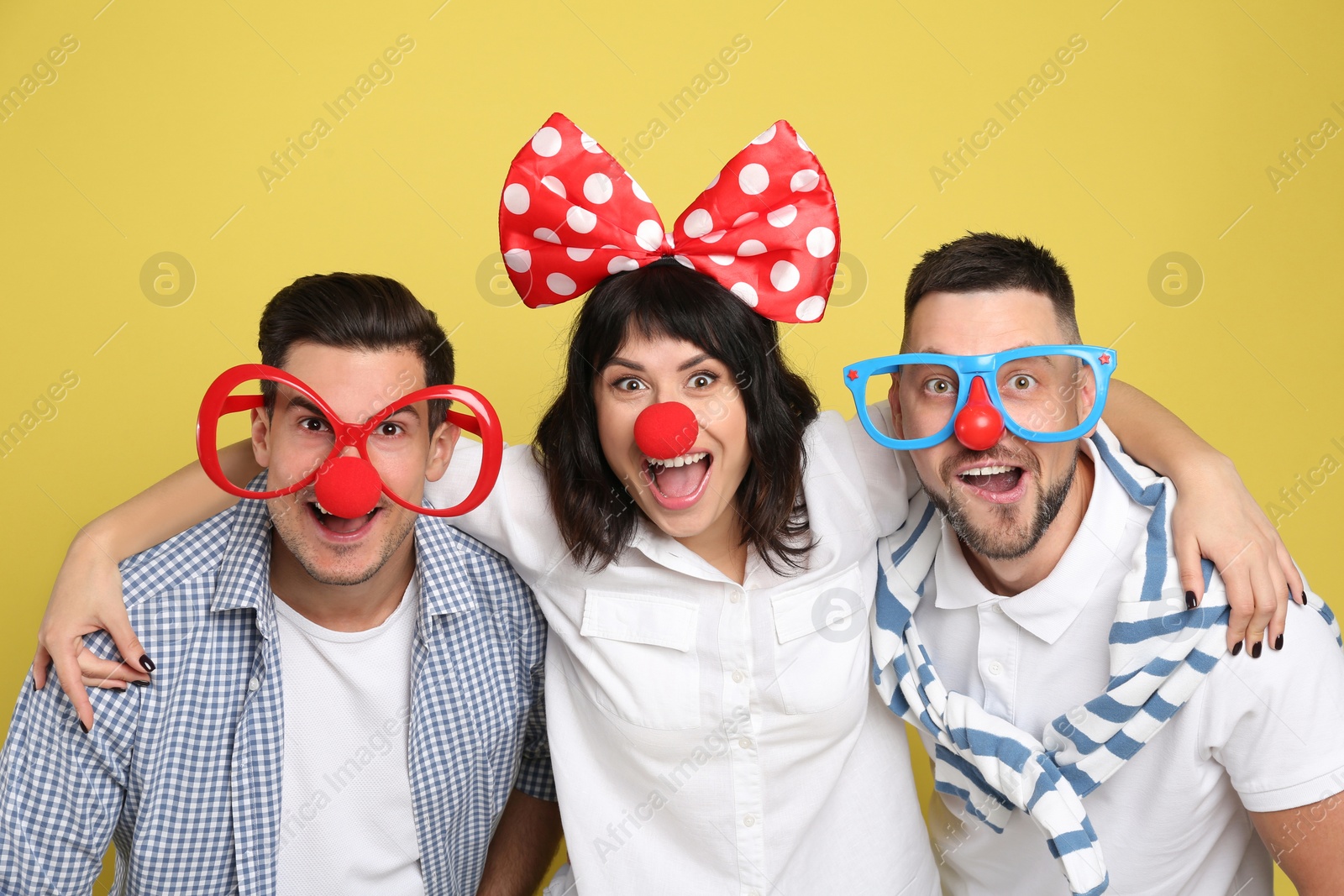 Photo of Group of friends with funny accessories on yellow background. April fool's day