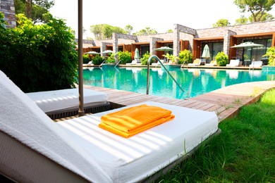 Photo of Sunbeds near outdoor swimming pool at luxury resort