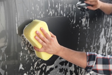 Worker cleaning automobile with sponge at car wash