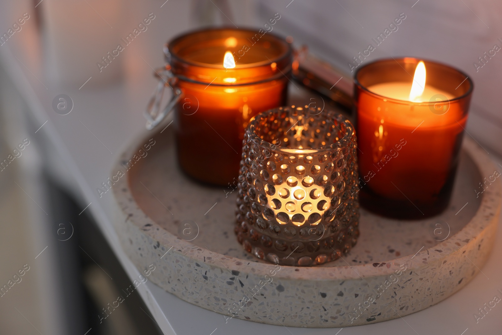 Photo of Burning candles on mantel near white wall indoors