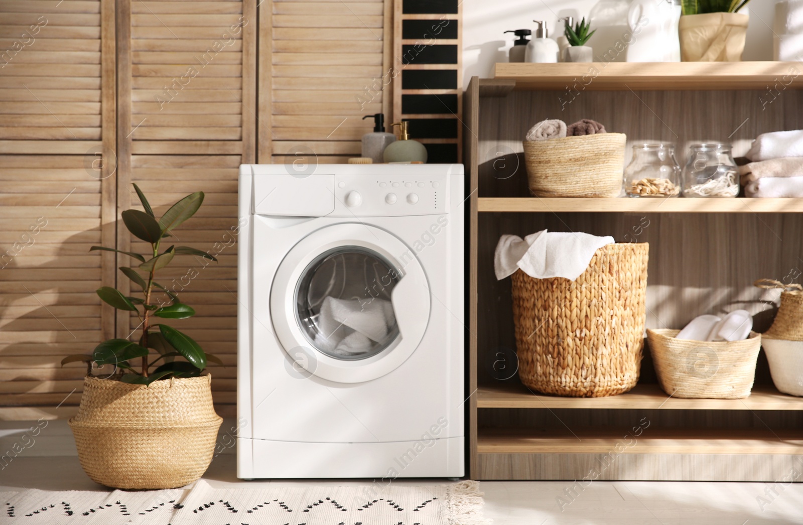 Photo of Modern washing machine and shelving unit in laundry room interior