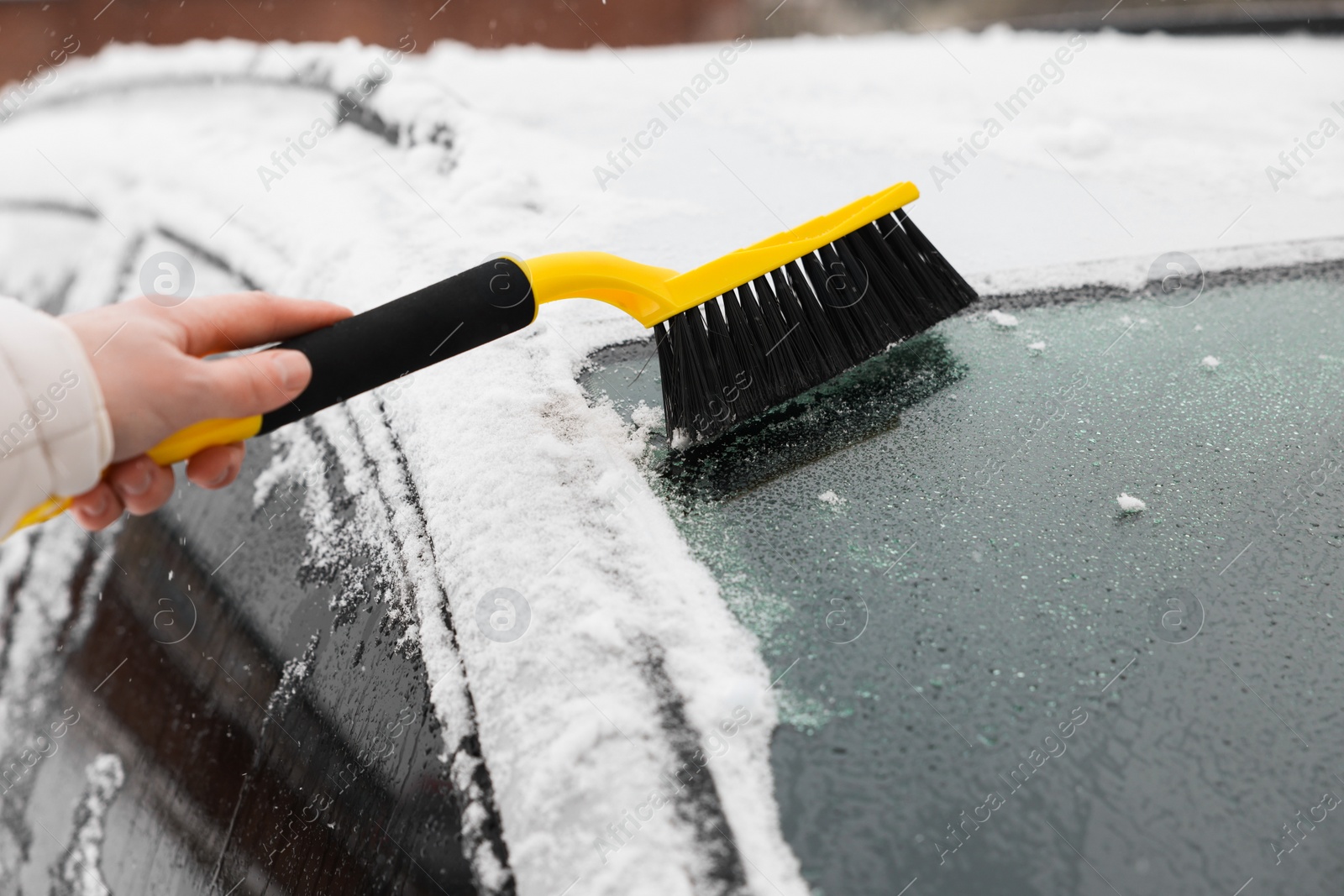 Photo of Man cleaning snow from car windshield outdoors, closeup