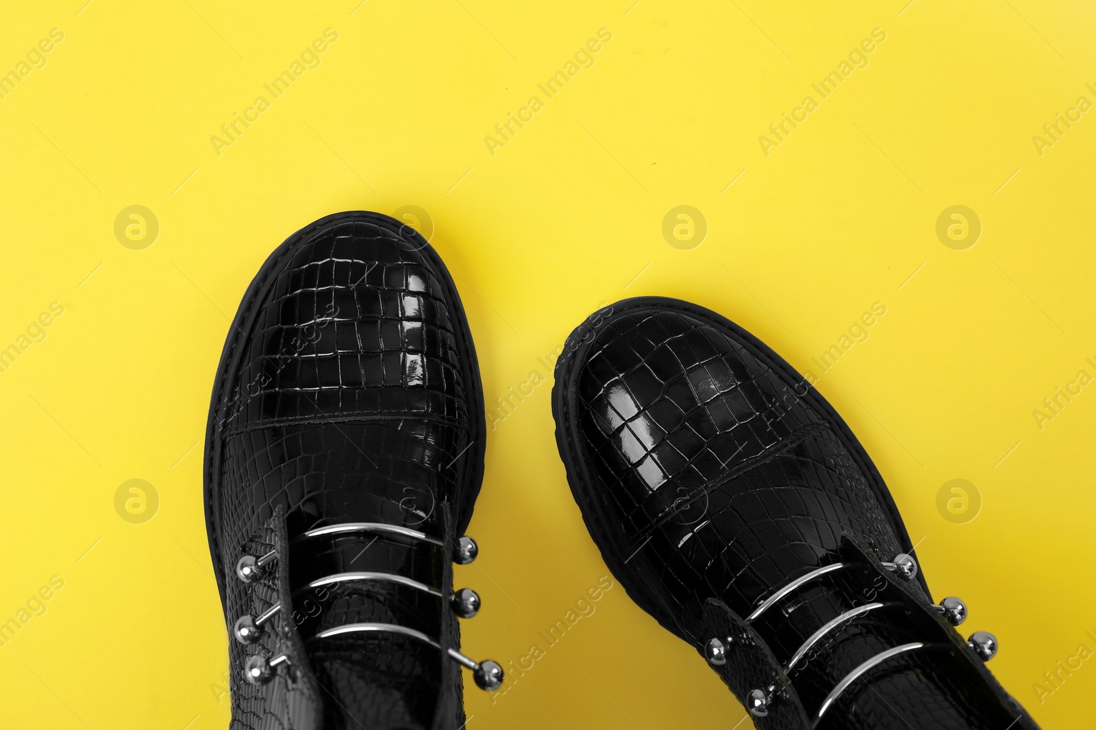 Photo of Pair of stylish ankle boots on yellow background, top view