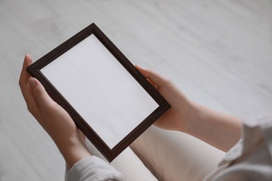 Photo of Woman holding empty photo frame indoors, closeup