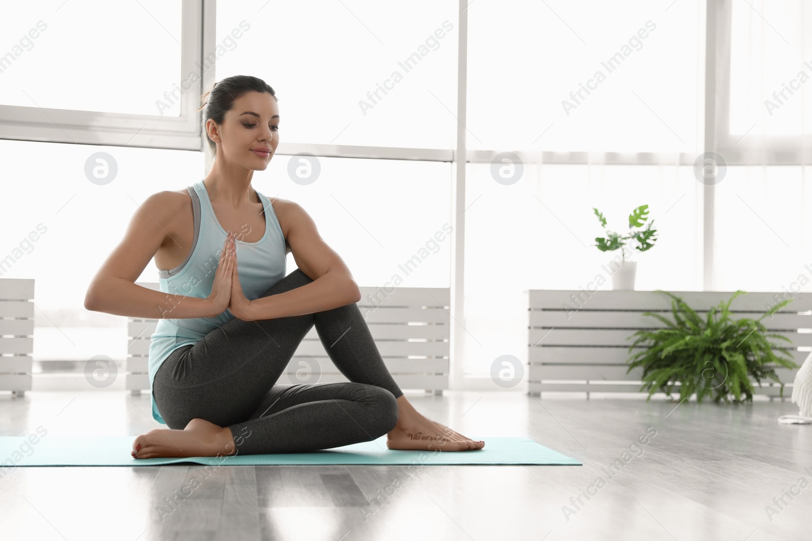 Photo of Young woman practicing lord of fishes asana in yoga studio. Matsyendrasana pose