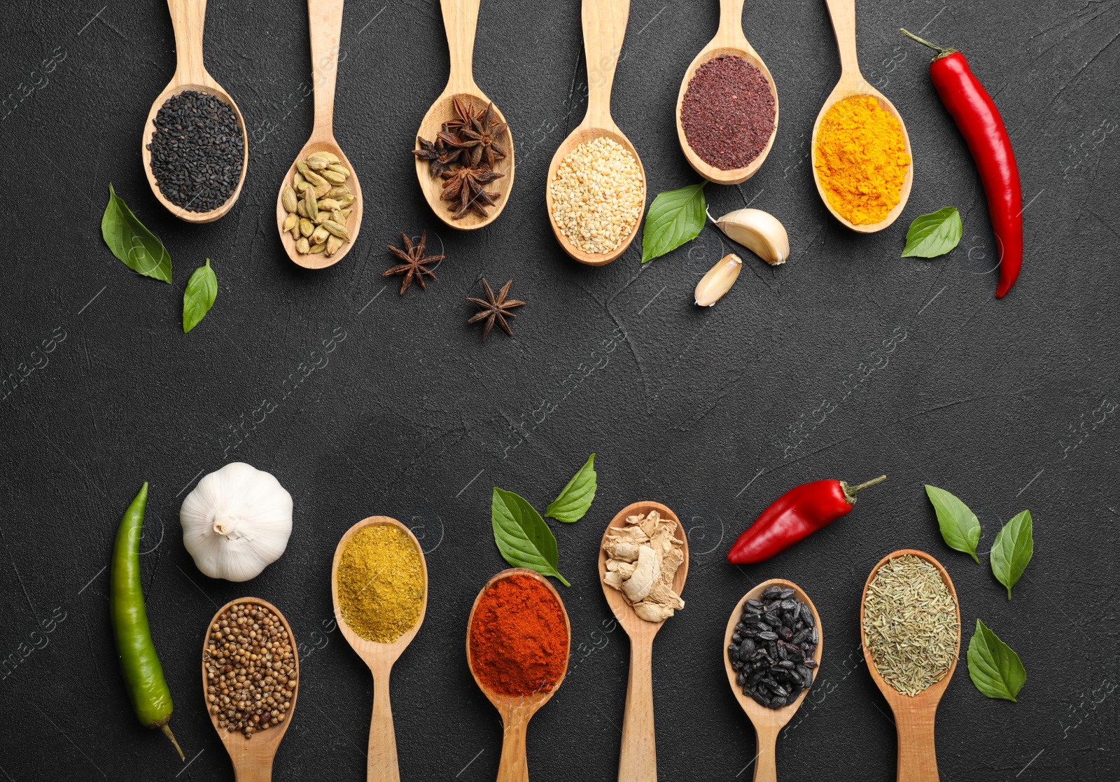 Photo of Composition with different aromatic spices in wooden spoons on dark background