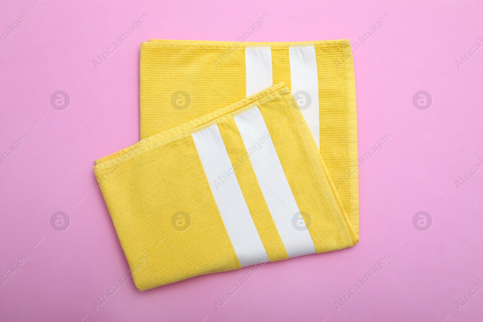 Photo of Folded striped beach towel on pink background, top view