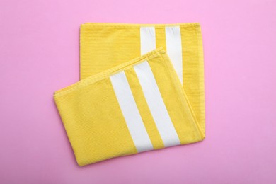 Folded striped beach towel on pink background, top view