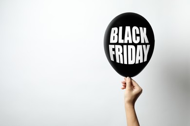 Woman holding balloon with phrase BLACK FRIDAY on white background, space for text