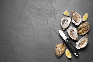 Photo of Fresh oysters with lemon and knife on black table, flat lay. Space for text