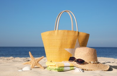 Bag and beach accessories on sand near sea