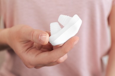 Photo of Woman holding anti-snoring device for nose, closeup