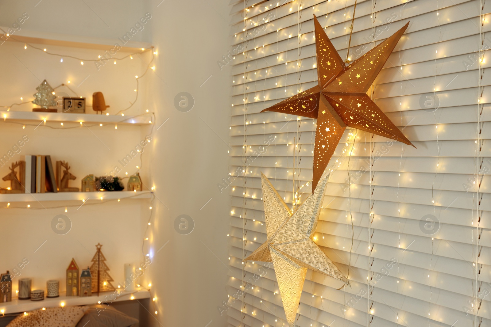 Photo of Beautiful decorative stars and festive lights in room. Christmas atmosphere