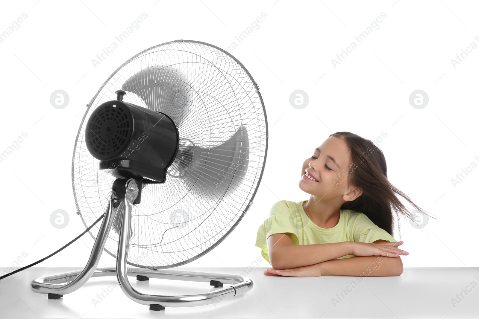 Photo of Little girl enjoying air flow from fan on white background. Summer heat