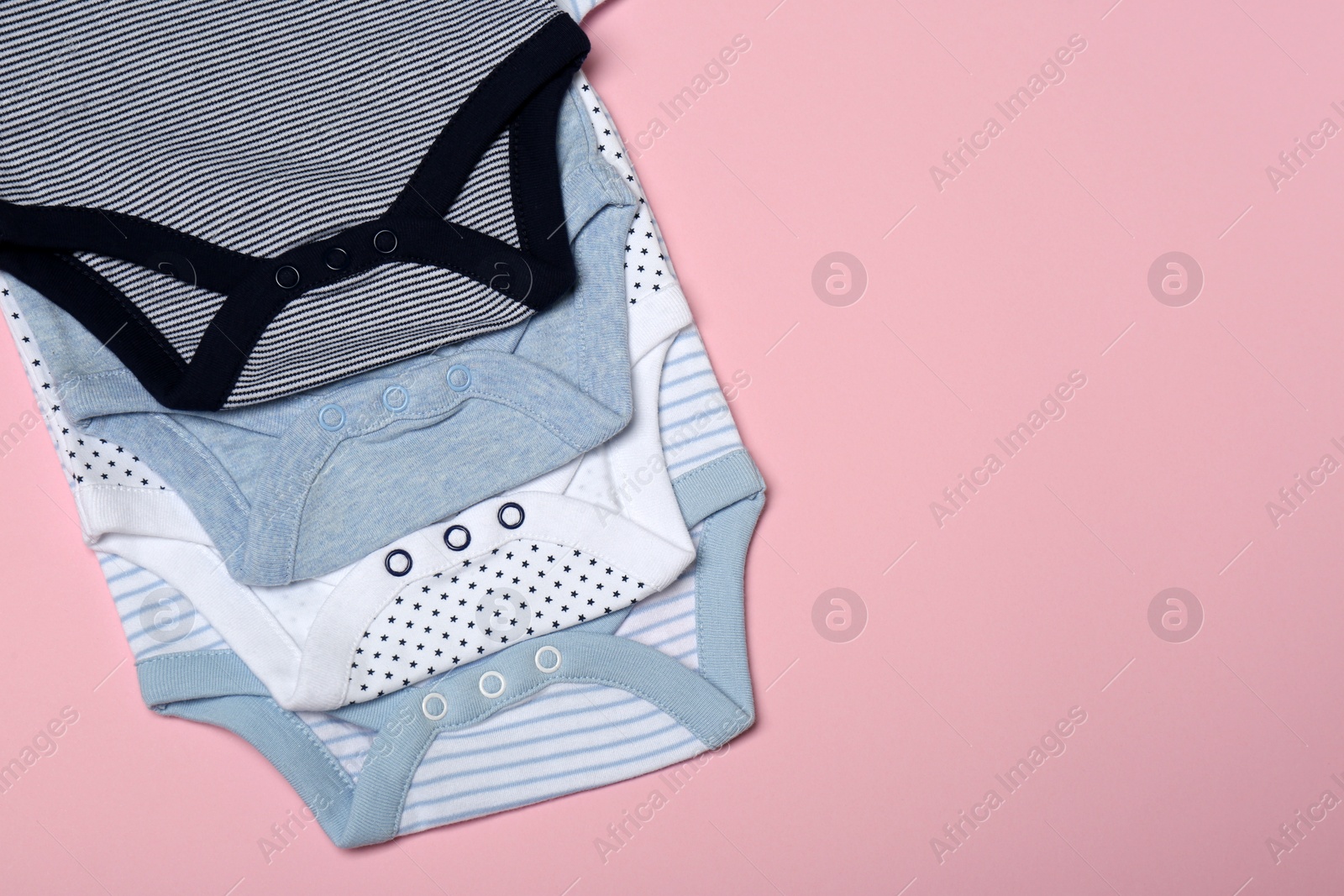 Photo of Cute baby onesies on color background, above view. Space for text