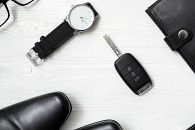 Flat lay composition with male accessories and car key on white wooden background