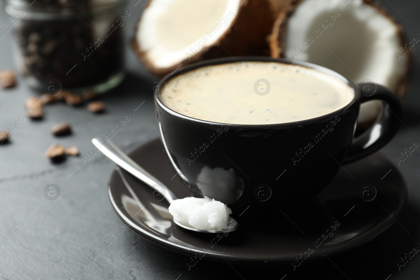 Photo of Delicious coffee with organic coconut oil on grey table