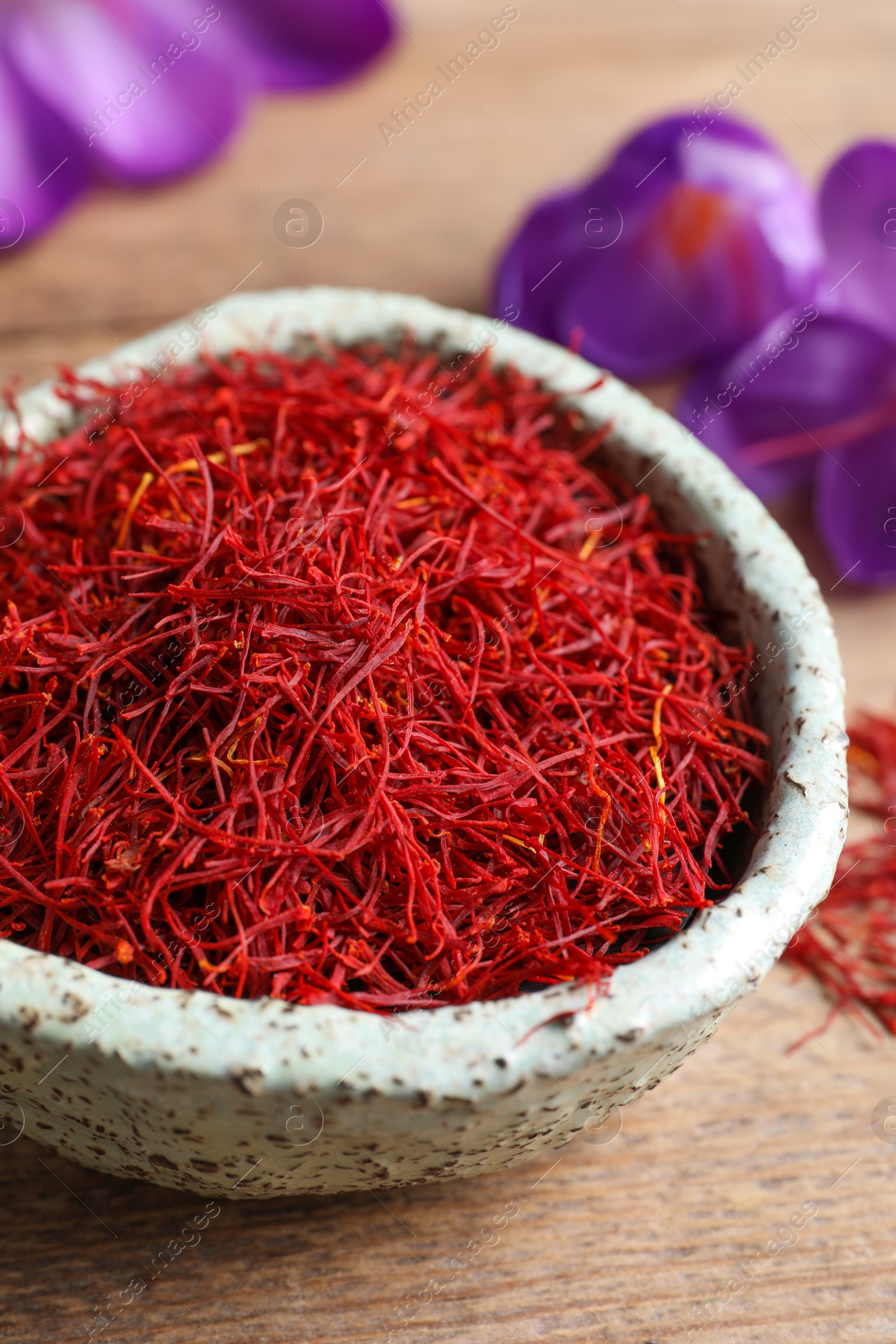 Photo of Dried saffron and crocus flowers on wooden table, closeup