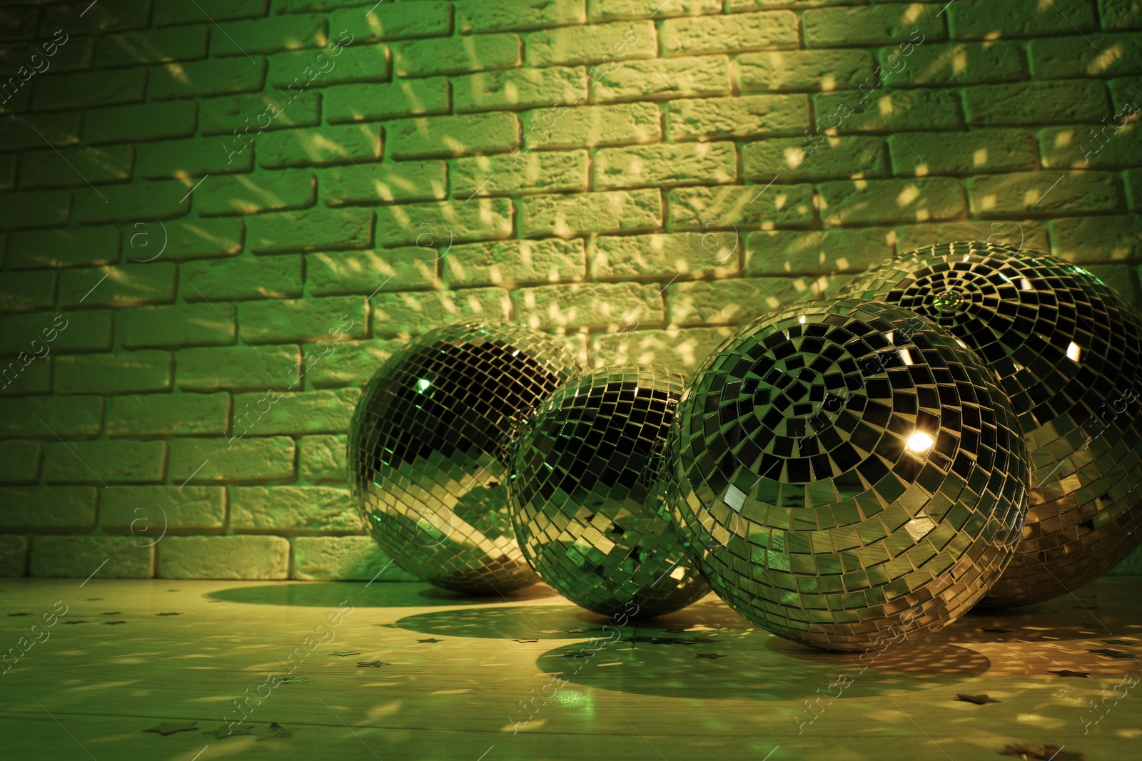 Photo of Many shiny disco balls near brick wall indoors, toned in green. Space for text