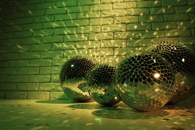 Photo of Many shiny disco balls near brick wall indoors, toned in green. Space for text