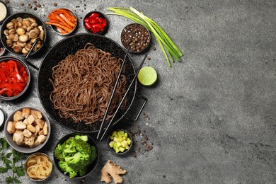 Photo of Wok with noodles, chicken and other products on grey table, flat lay. Space for text