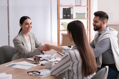 Real estate agent shaking hands with client in office. Mortgage concept