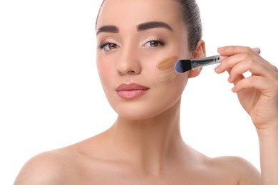 Photo of Woman applying foundation on face with brush against white background