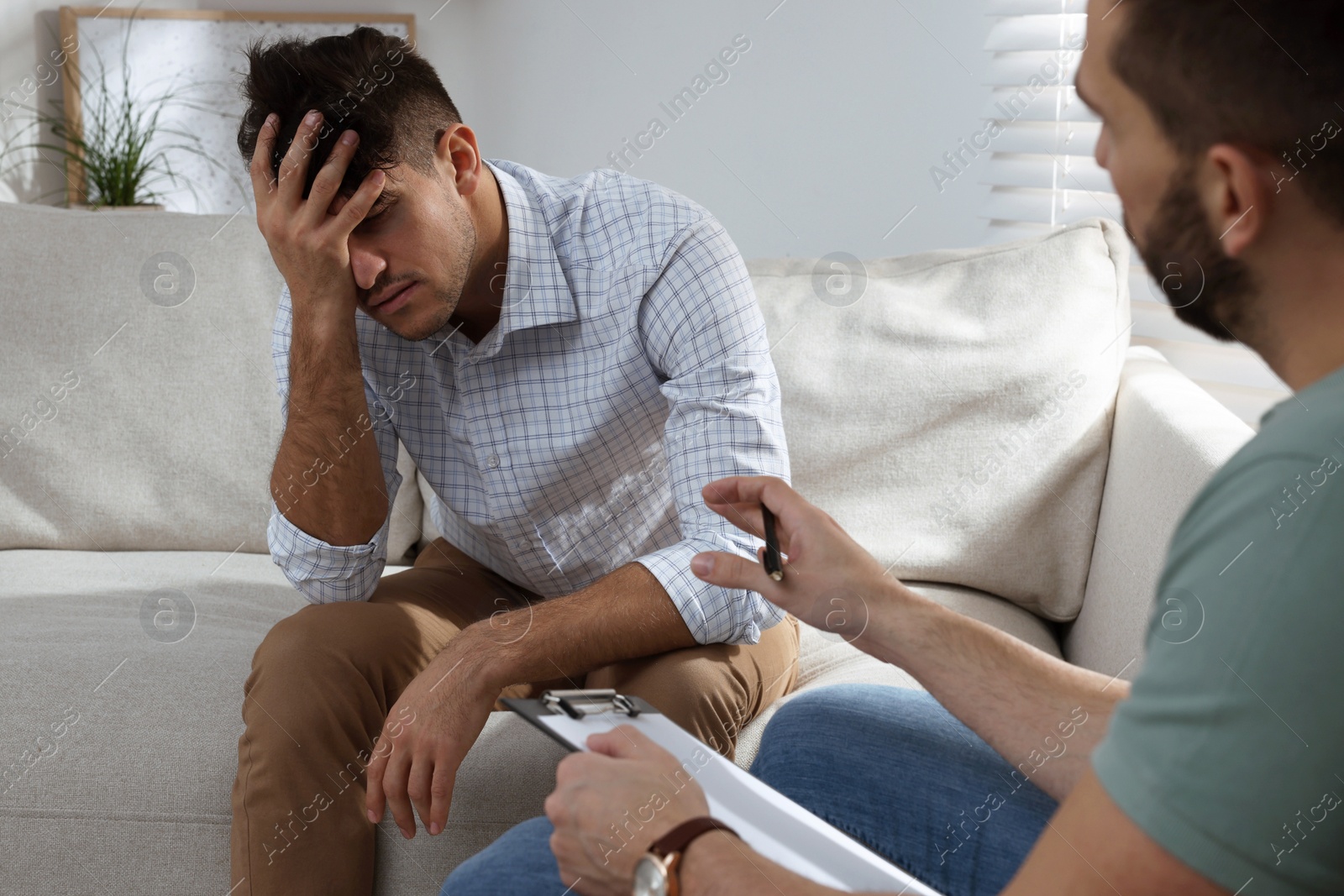 Photo of Unhappy man having session with his therapist indoors