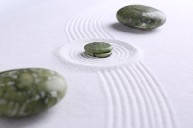 Photo of Zen concept. Stones and pattern on white sand, closeup