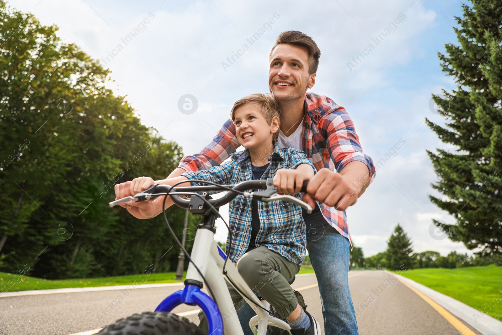 Photo of Dad teaching son to ride bicycle outdoors