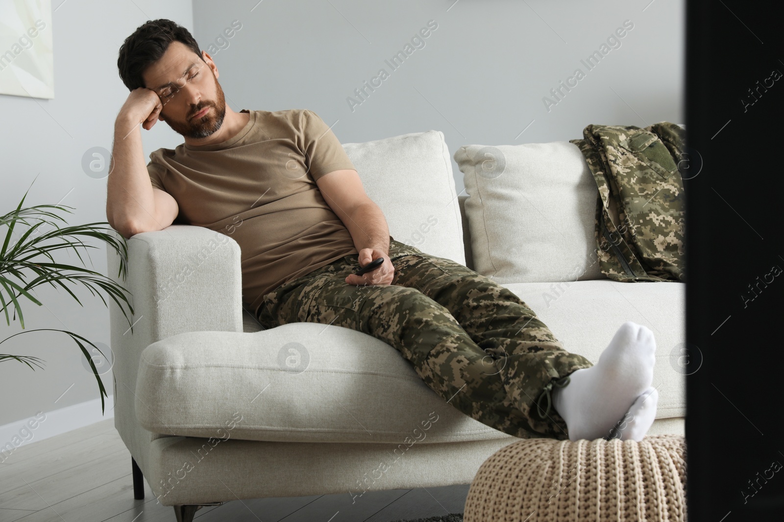 Photo of Soldier napping on soft sofa near TV in living room. Military service