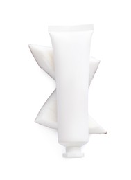 Tube of hand cream and coconut pieces on white background, top view