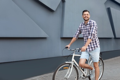 Photo of Man with bicycle on street near gray wall